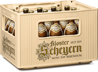 Ein Kasten mit zwölf Bierflaschen steht auf einem Tisch. Der Kasten und die Flaschenetiketten haben goldene und schwarze Elemente.